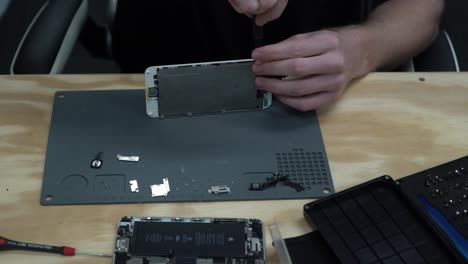 hombre reparando la pantalla del iphone y reemplazando los tornillos