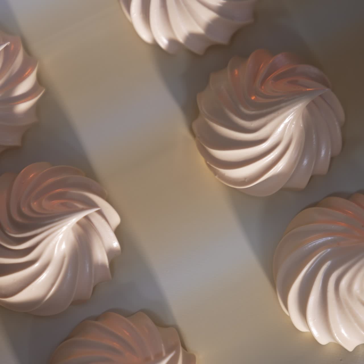 Beautifully shaped white creamy marshmallows moving slowly on conveyor belt. View from above. Close up