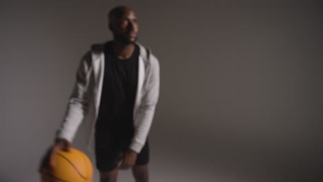 Defokussierte-Studioaufnahme-Eines-Männlichen-Basketballspielers,-Der-Vor-Dunklem-Hintergrund-Dribbelt-Und-Den-Ball-Wirft