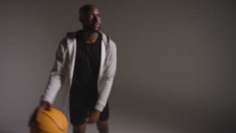 disparo de estudio desenfocado de un jugador de baloncesto masculino dribbling y lanzando la pelota contra un fondo oscuro