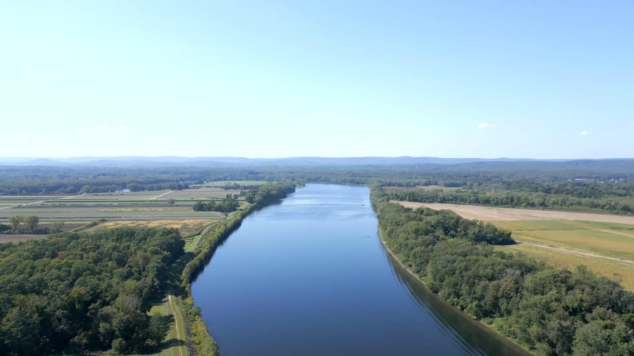 Suburb neighborhood near Connecticut River in Hadley, Massachusetts. Farm fields and green garden of houses in USA. Aerial panning wide shot