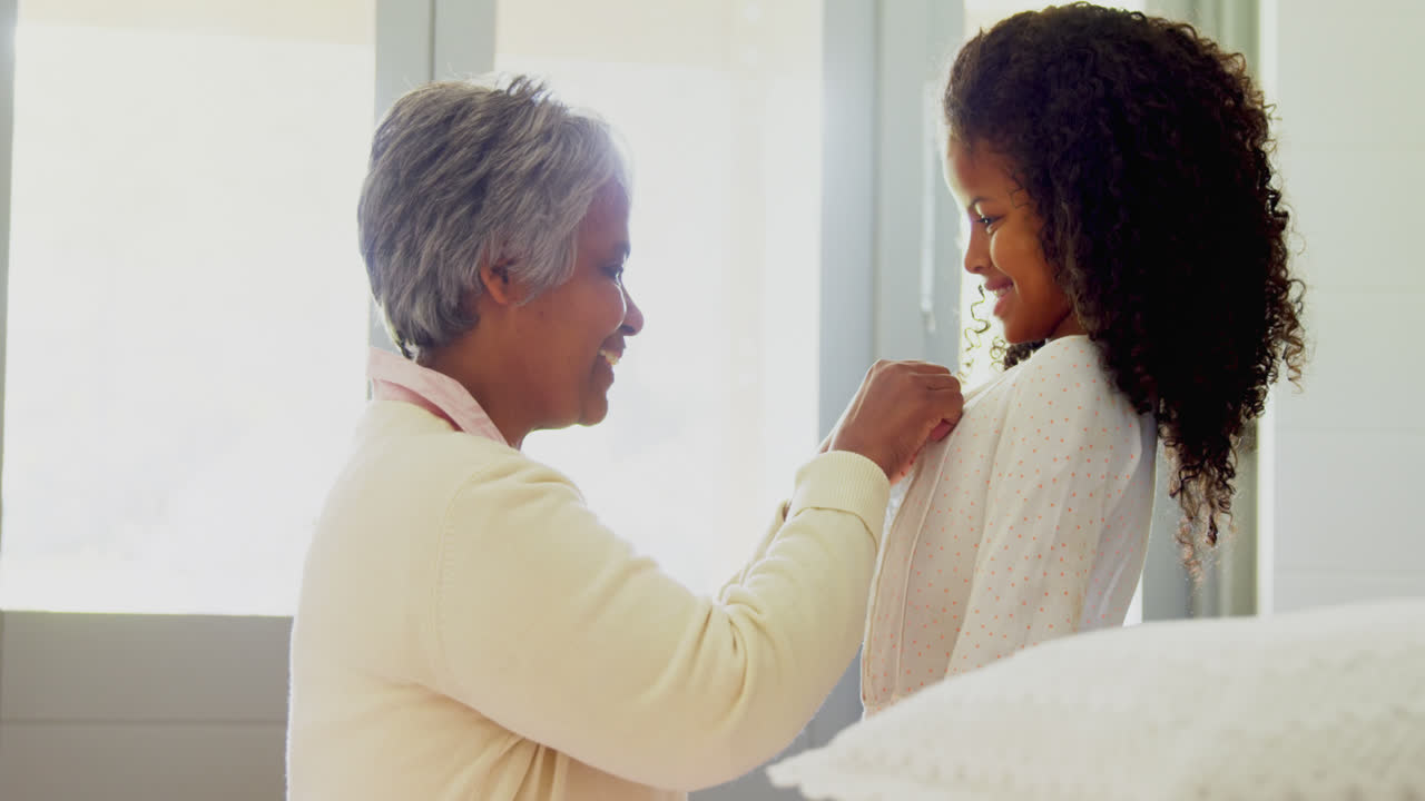 할머니가 침실 4k에서 손녀를 옷을 입히고 있습니다.