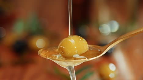 olive oil drizzled over olives on spoon
