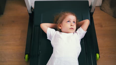 girl in t-shirt lies on running machine listening to music