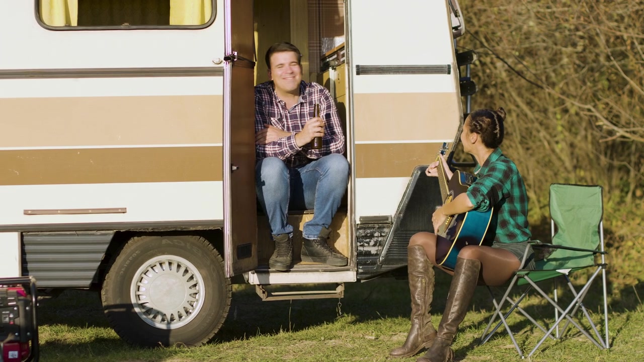 Donna canta e suona la chitarra accanto al camper