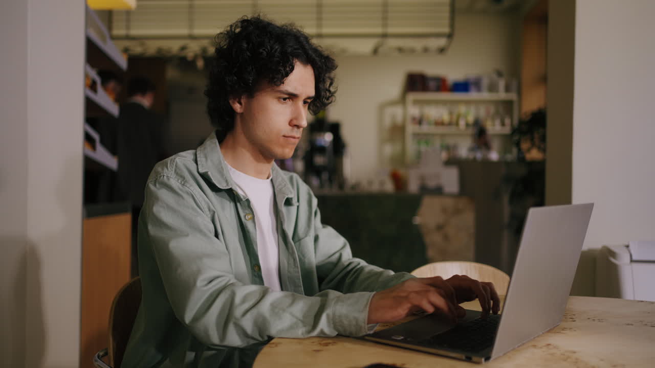 hombre trabajando en una computadora portátil en un café