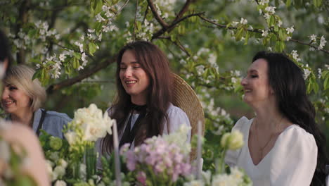 joyful female friends are sitting at table in garden and talking cheerfully happy women in party