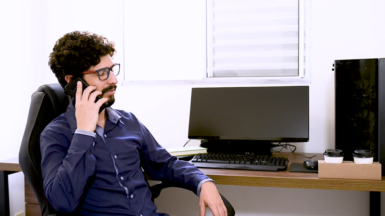 Hombre latino conversando por teléfono en la oficina.