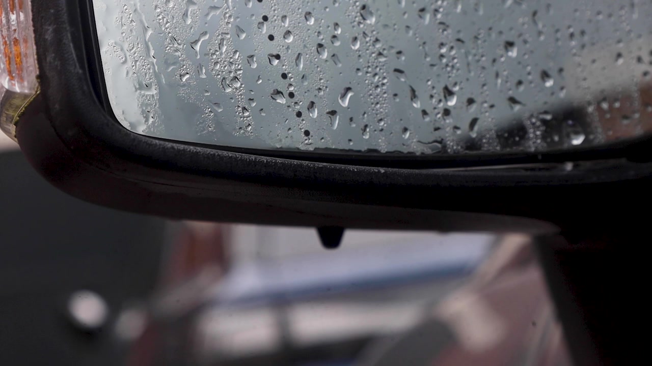 Video di un'auto con specchietto laterale e goccioline d'acqua che cadono.