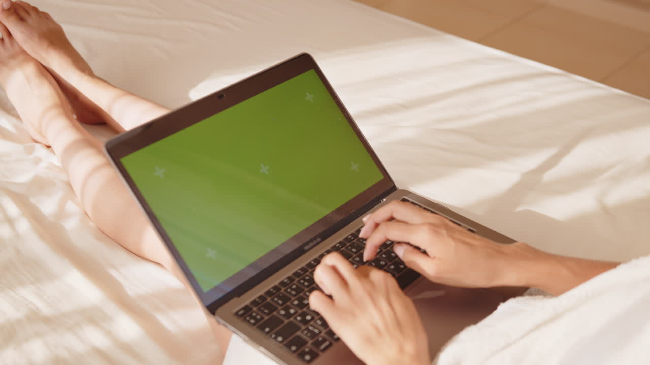 Woman relaxing on bed working on laptop