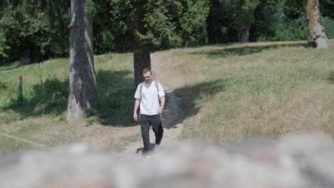 young man walking with guitar on street near forest