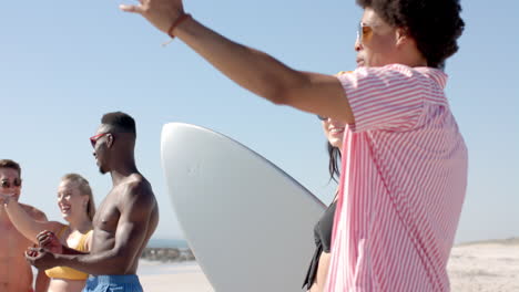 Young-Caucasian-woman-chats-with-a-young-Biracial-man-at-the-beach