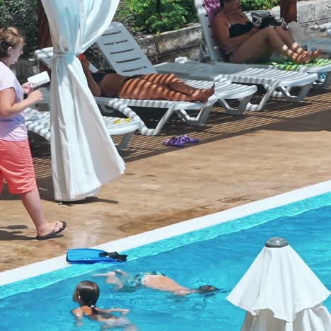 personas sentadas a la orilla de la piscina de un resort durante las vacaciones de verano