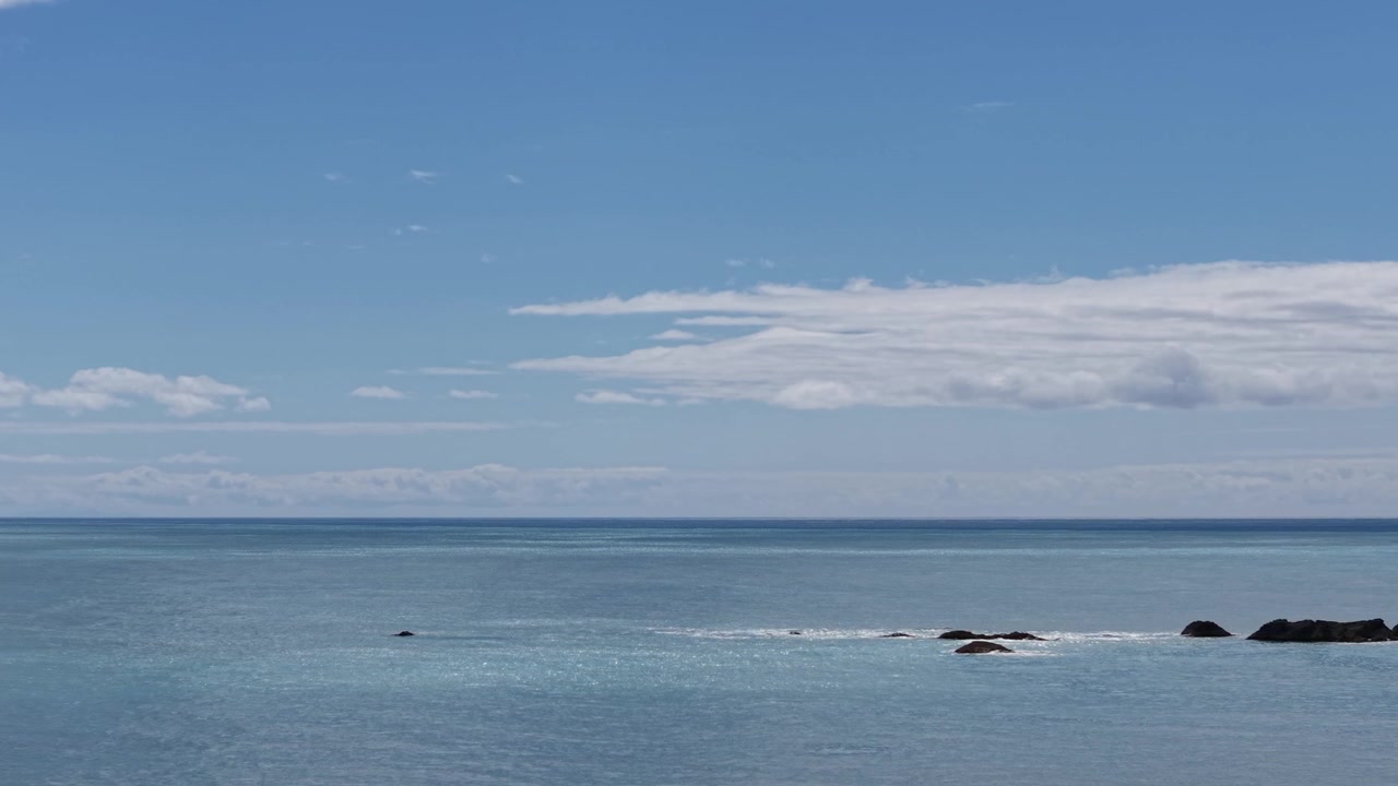 沖合の岩に沿って飛行し、薄い青色の海に太陽の光がきらめく（スローモーション） - ケケレング海岸、カイコウラ地域。