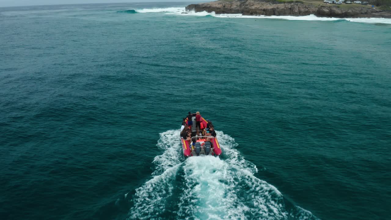 Tracking then upwards panning drone shot of a boat heading towards a surf spot in Tofo, Mozambique.