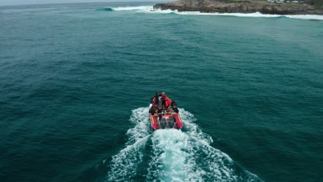 tracking then upwards panning drone shot of a boat heading towards a surf spot in tofo, mozambique.