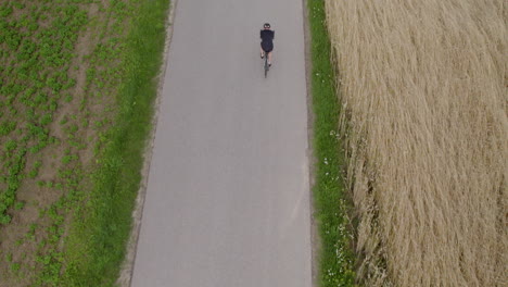 a top-down drone shot of a cyclist riding on an empty narrow asphalt path