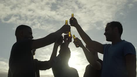 smiling friends cheering with beer bottles and talking