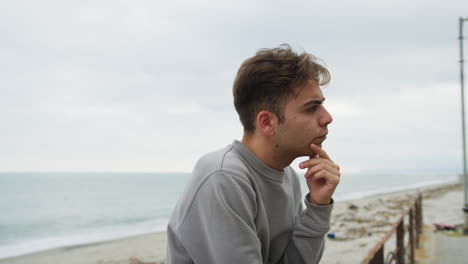 boy with pensive expression on his face looks toward the horizon on the beach