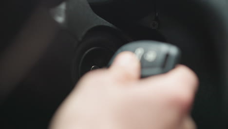close up of commuter inserting metal key into ignition starter and turning key inside vehicle cabin focusing on hand movement dashboard detail and jacket sleeve during winter commute preparation