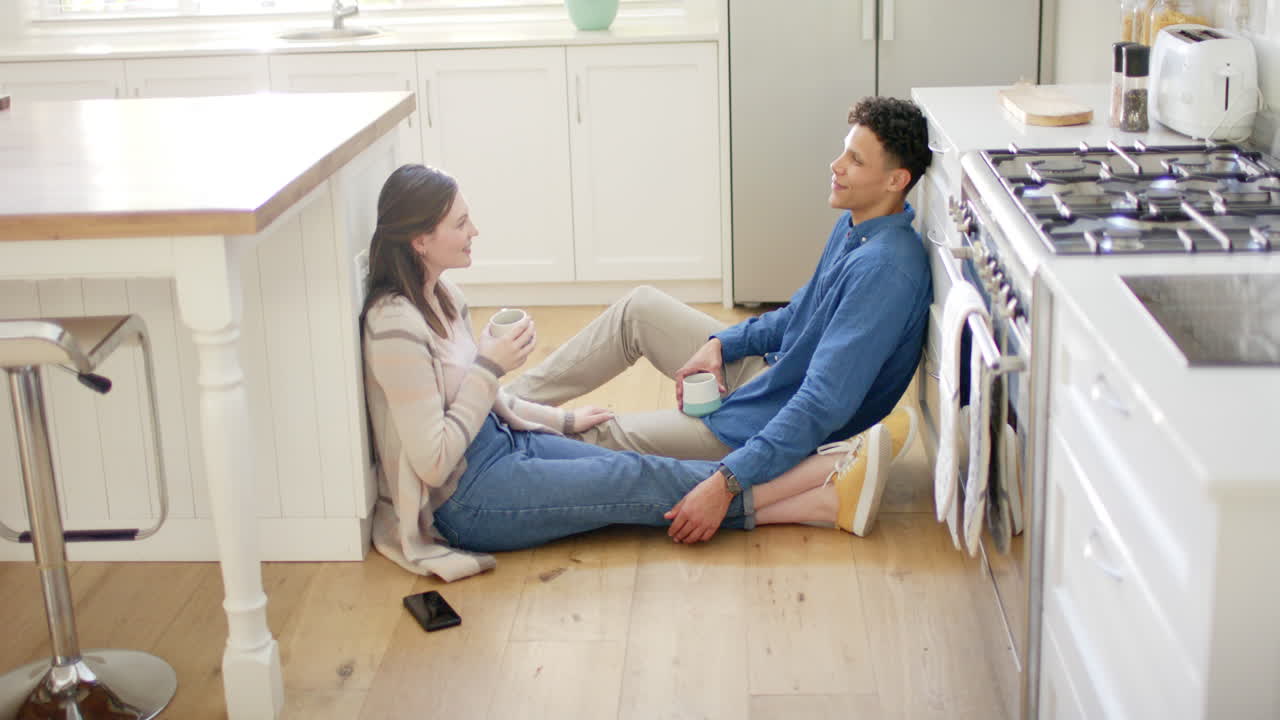 다양한 행복한 커플이 커피를 마시며 이야기하고 집에서 부 바닥에 앉아서 느린 동작을 하고 있습니다.