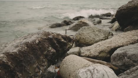 large rocks on the shore with splashing waves during daytime