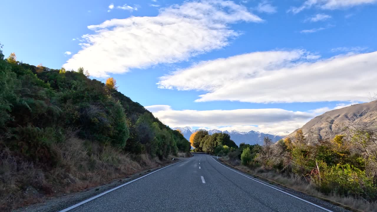 Forward-facing drive through mountain landscape, natural daylight, smooth camera movement, clear blue sky