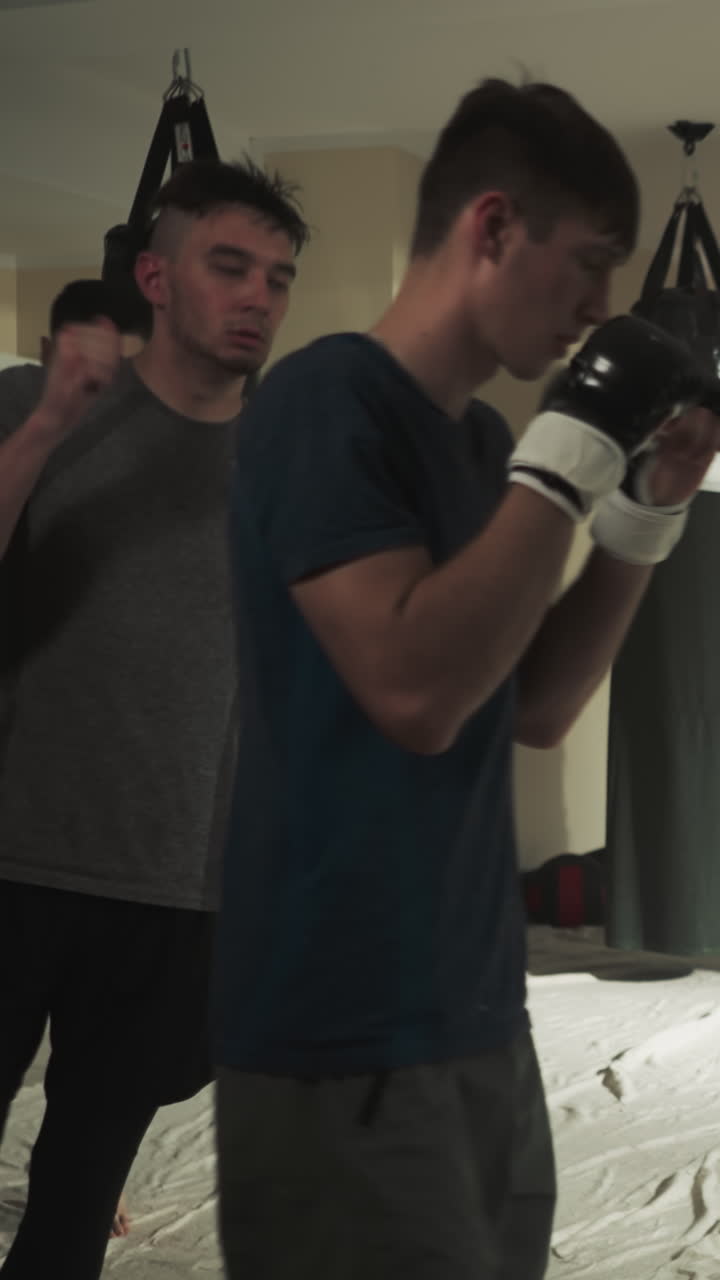 Sportsmen group runs around boxing gym. Kick-boxer team trains together on rink in combat club slow motion. Men warm up before fighting indoors