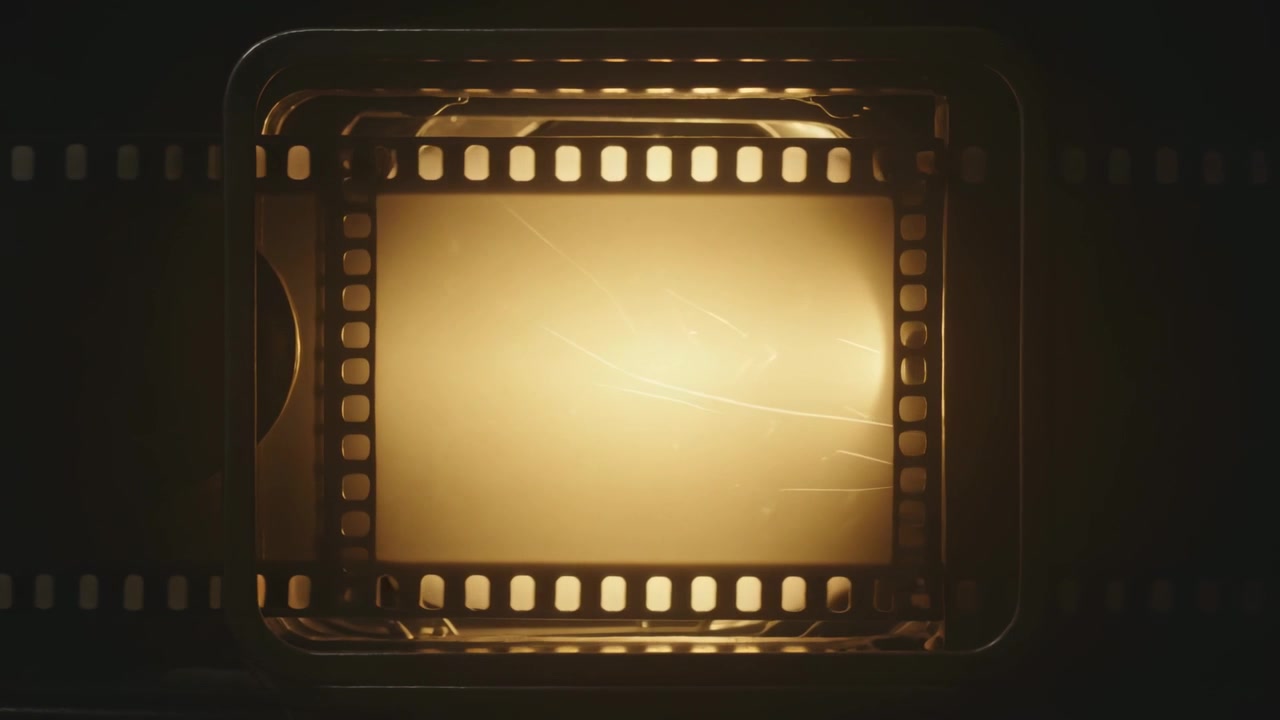 Een motor beweegt een filmbeeld in een lade over een achtergrondverlichting voor inspectie, met krassen en perforaties.