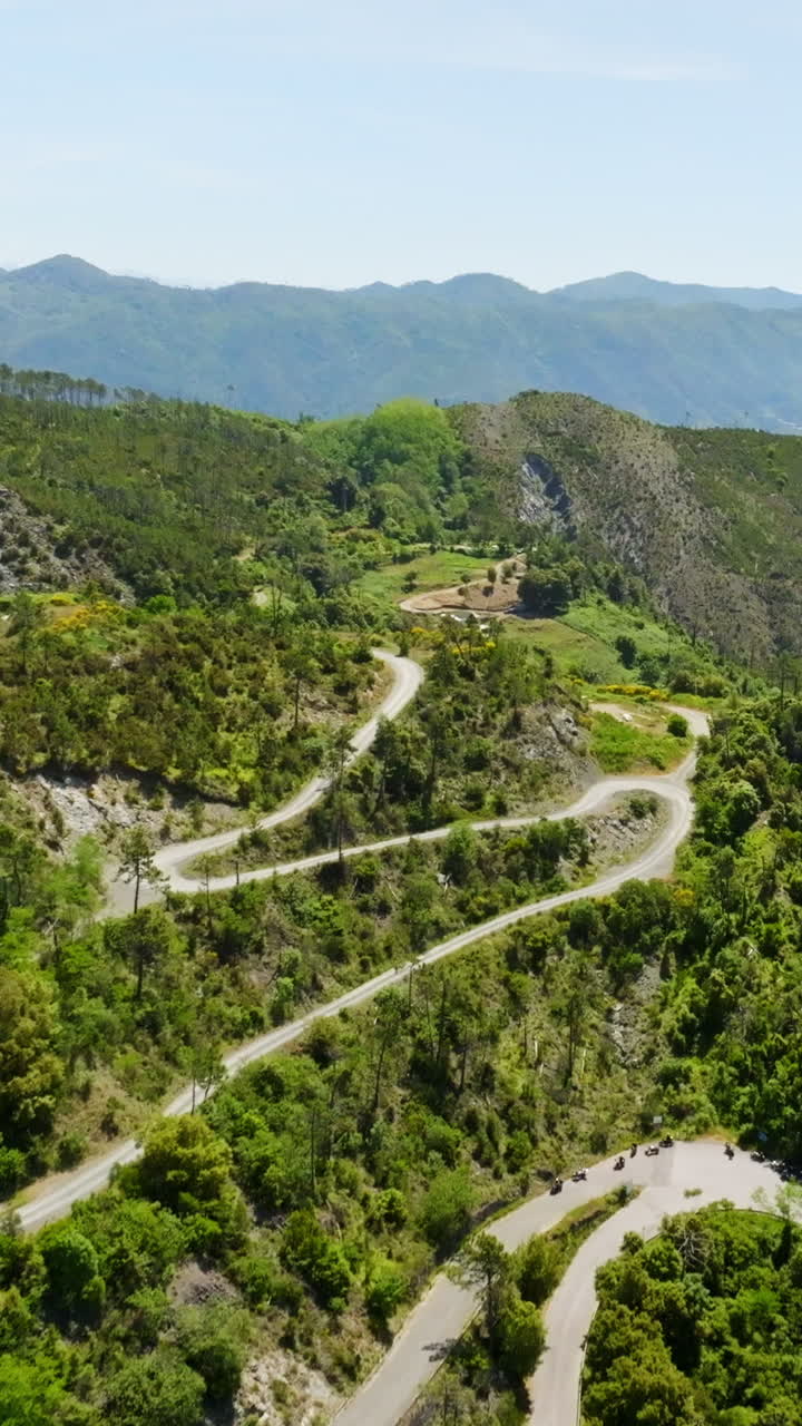 Vertical drone shot of a winding road in the mountains of Liguria, in sunny Italy