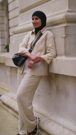 Vertical-Video-Portrait-Of-Smiling-Muslim-Businesswoman-Wearing-Hijab-And-Modern-Business-Suit-Standing-Outside-City-Office-Buildings-5