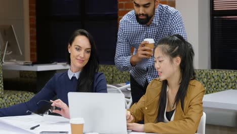 Executives-discussing-over-laptop-in-office-cafeteria-4k