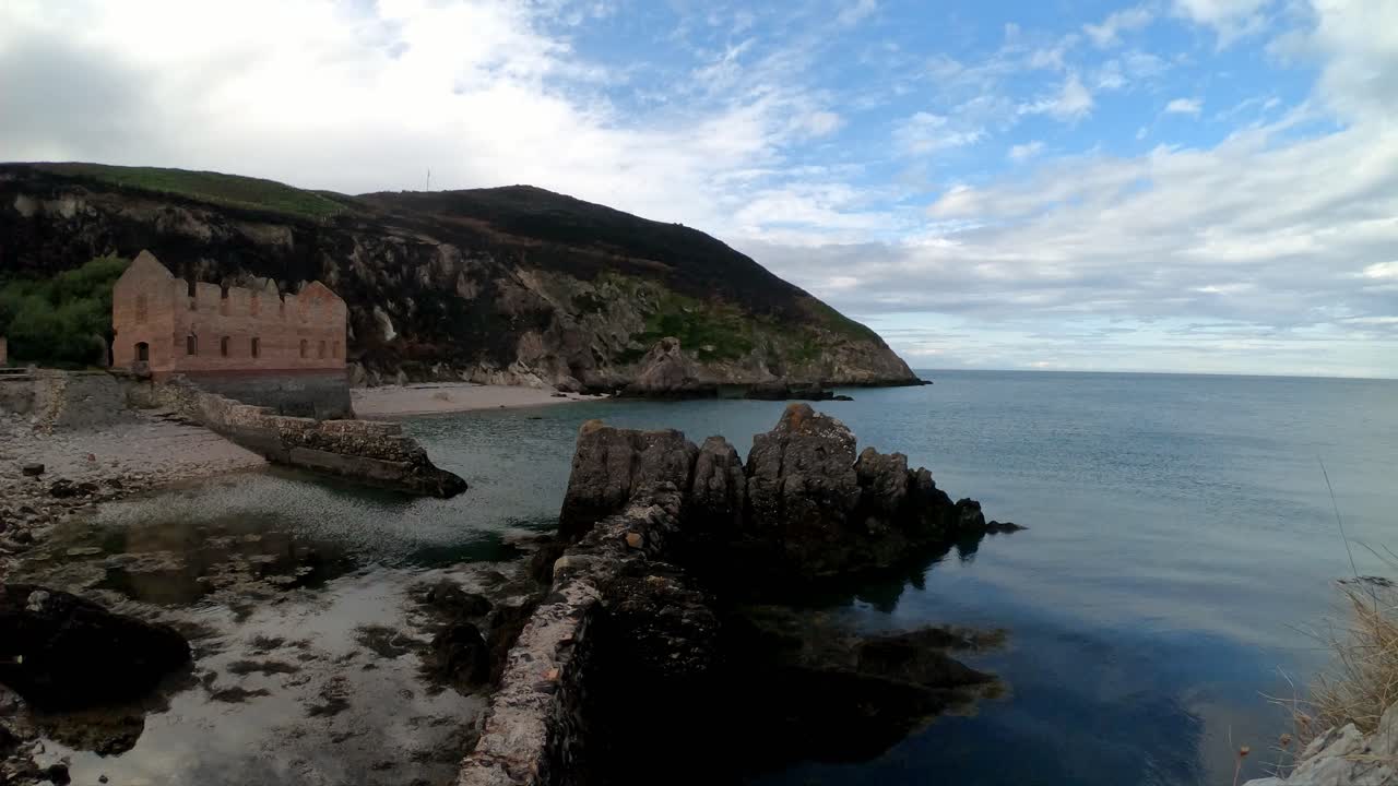 sitio abandonado de la fábrica de ladrillo galés lapso de tiempo con las nubes que pasan y la marea del océano lavando en la costa