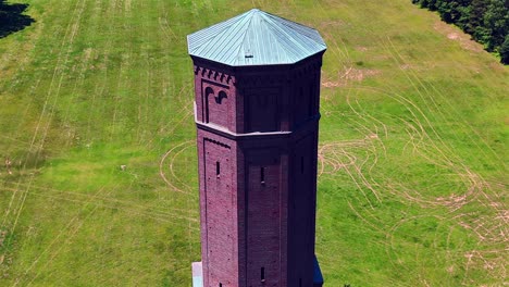 An-aerial-view-of-a-brick-water-tower-on-a-sunny-day-in-a-large-green-field-on-the-Pilgrim-Psychiatric-Center-property-on-Long-Island,-NY