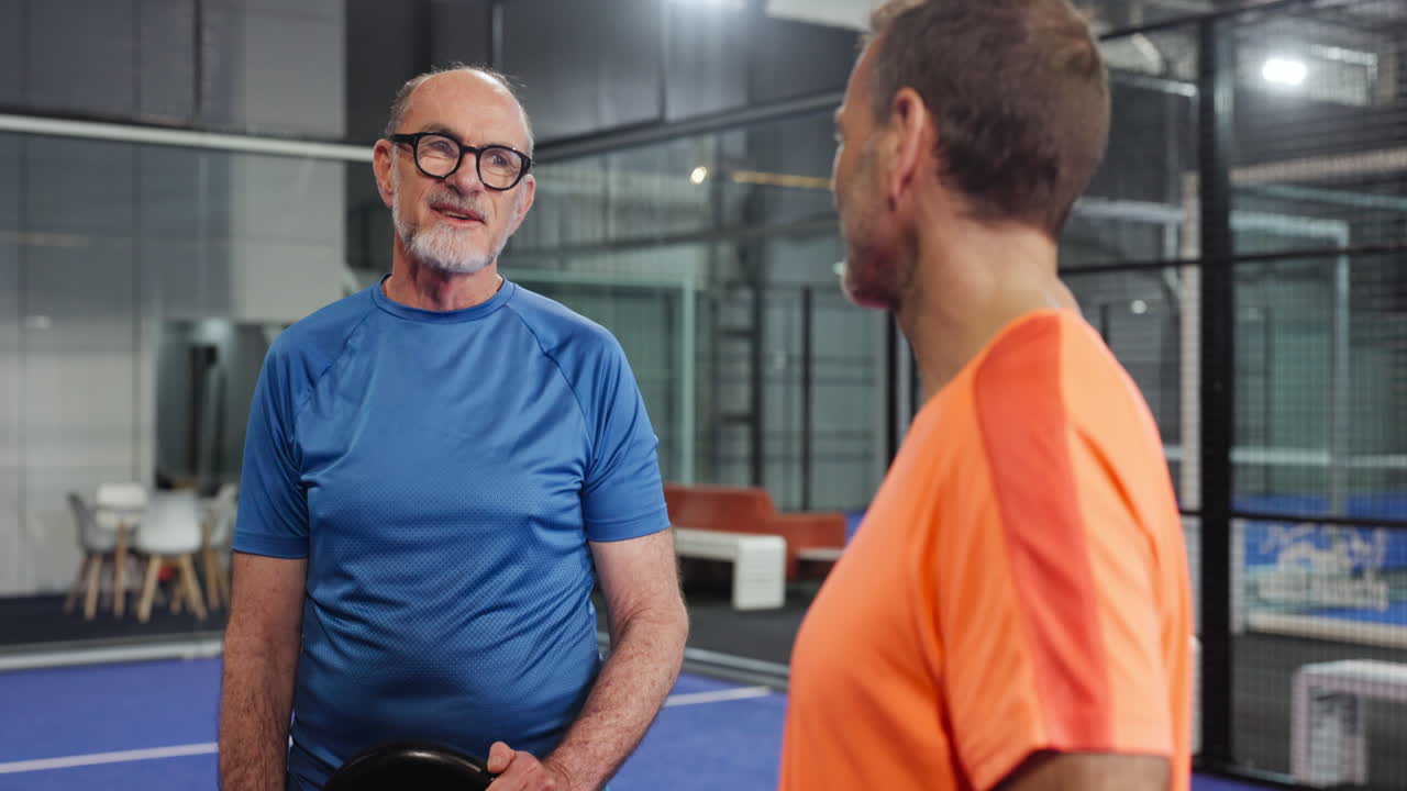 Deux hommes jouant au padel en salle