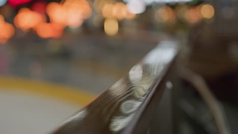 a close-up view of a polished handrail with a very blurry skiing area in the background.atmosphere of the skiing area in the background