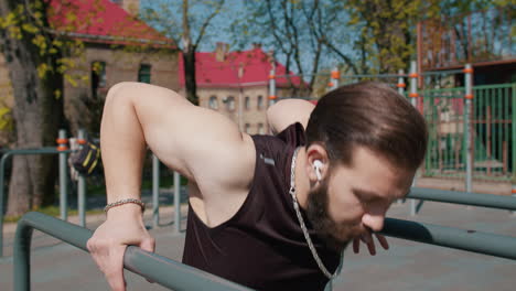 hombre haciendo inmersiones en barras paralelas en un gimnasio al aire libre