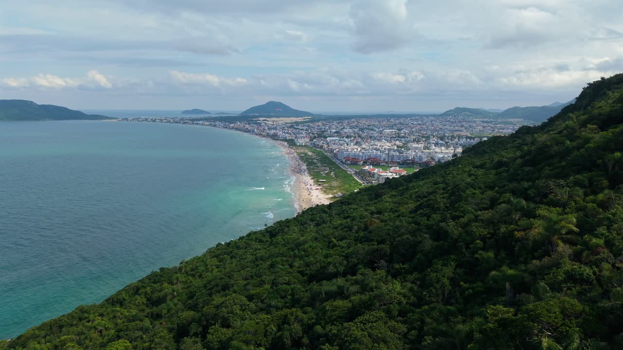 Pemandangan udara drone di Pantai Praia dos Ingleses, Florianopolis, Brasil, menampilkan pantai, perbukitan, laut, dan resor.