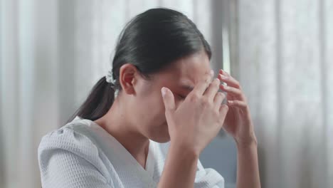 집에서 데스크에서 일하는 동안 두통을 고 있는 하우스 모델과 함께 아시아 여성 엔지니어의 클로즈업