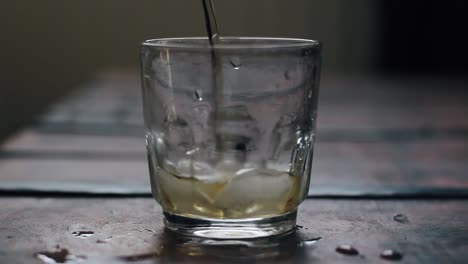 dropping ice cubes and pouring a drink in a dirty glass