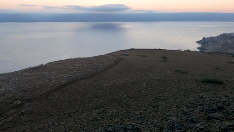 Picturesque-view-of-a-sunset-over-water-with-a-slow-pullback-over-a-dry-desolate-shore