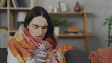 woman feeling ill, drinking tea at home