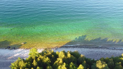 the shoreline is rocky and densely packed with bright green trees