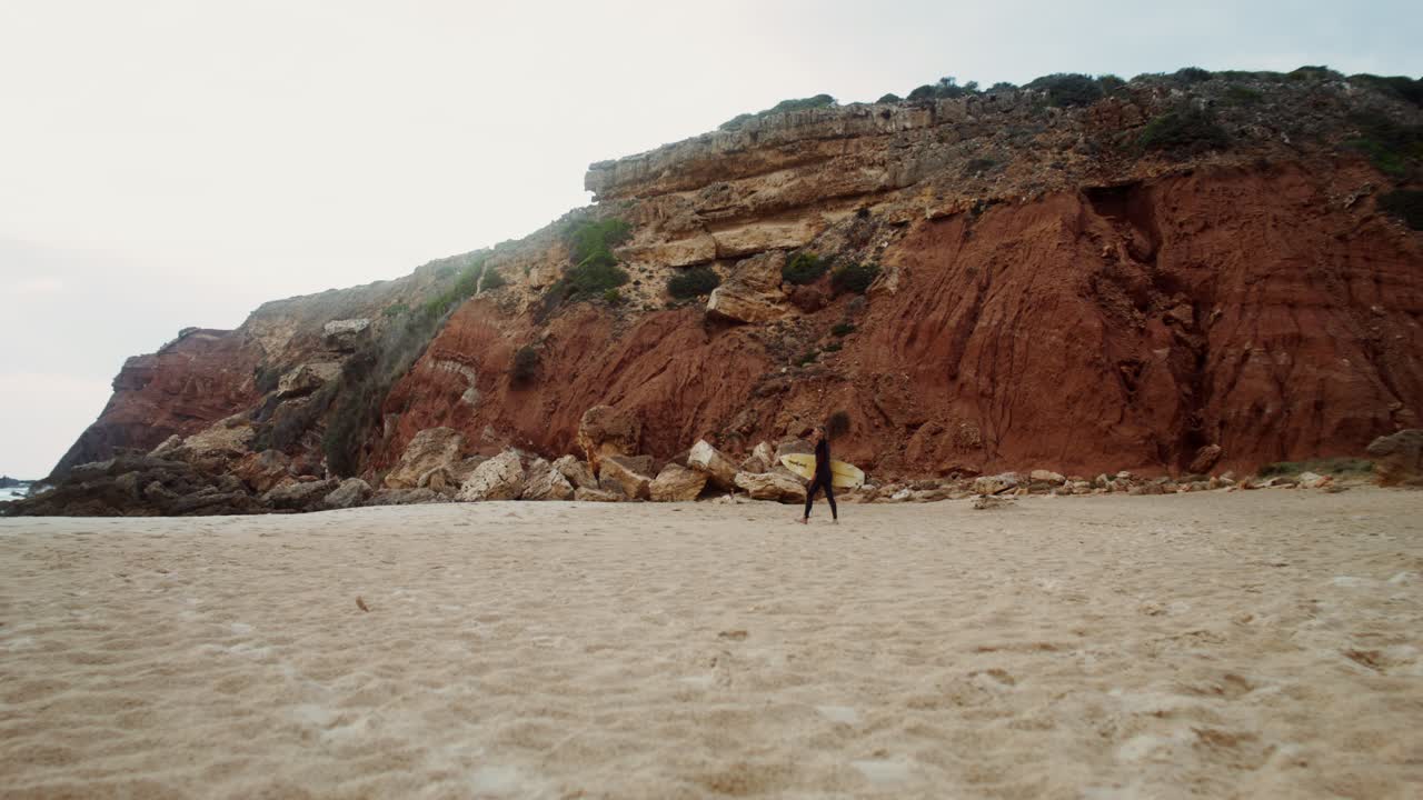surfista en una playa con acantilados rojos