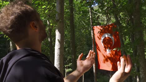 el joven que mira la bandera turca está orando.