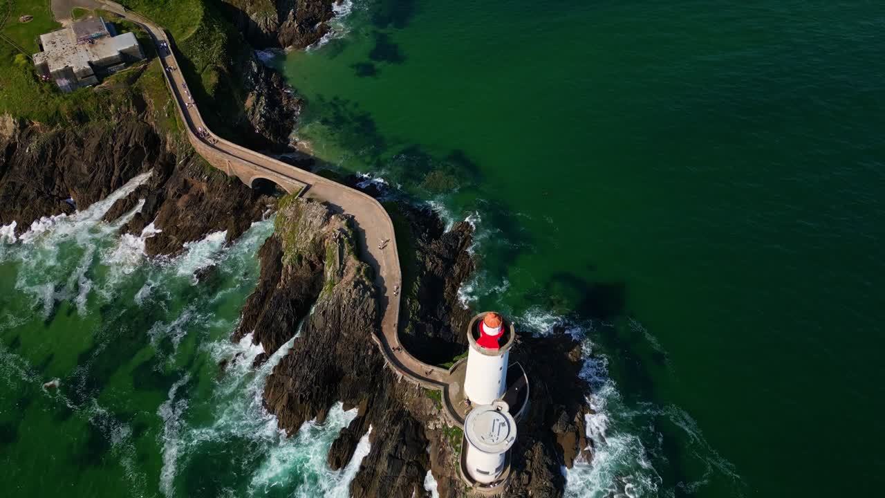 Drone shot in total top-down view pushing forward over Petit Minou lighthouse and the winding path leading to it, with waves crashing below. Brittany in France