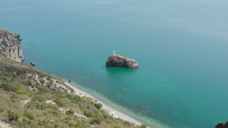 coastal view with a rock and cross in the turquoise water