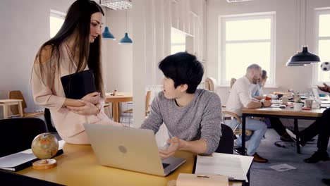 young asian worker talking to female team leader. happy mixed ethnicity colleagues enjoy healthy office atmosphere 4k