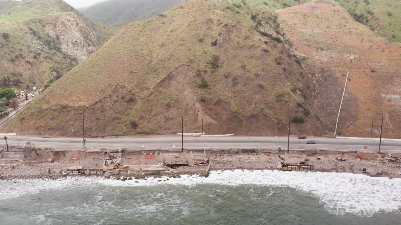 Aerial wide dolly shot of burned homes along Pacific Coast Highway in Malibu after the Palisades Fire in Los Angeles, California. 4K