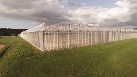 aerial view of an greenhouse near a field with blu sky on a sunny day